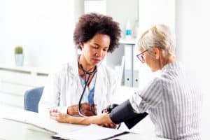 Doctor measure blood pressure in ambulance older woman